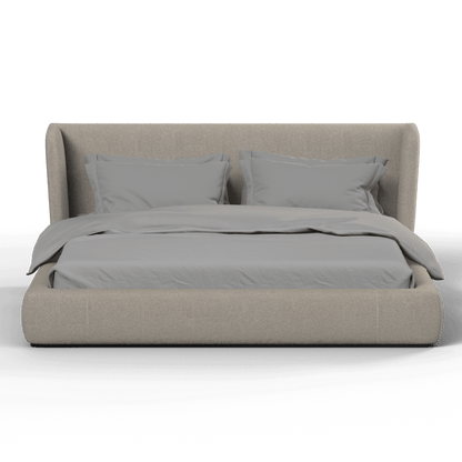 A modern low-profile bed with a cushioned frame in gray upholstery, featuring a wrap-around design. The bed is dressed with a gray comforter and has two matching pillows.